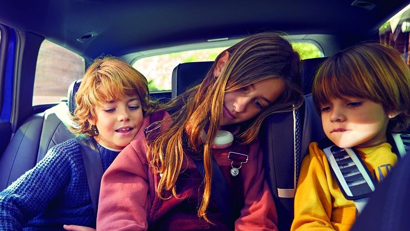 Familie auf einem Ausflug im Auto, Kinder nutzen ein Tablet.