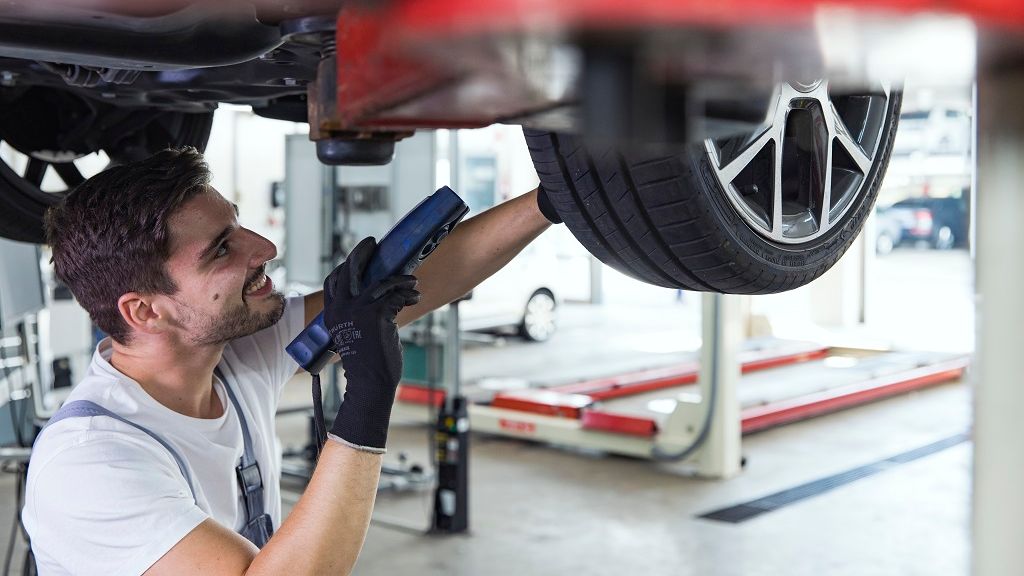 Mechaniker arbeitet an einem Auto unter der Hebebühne.