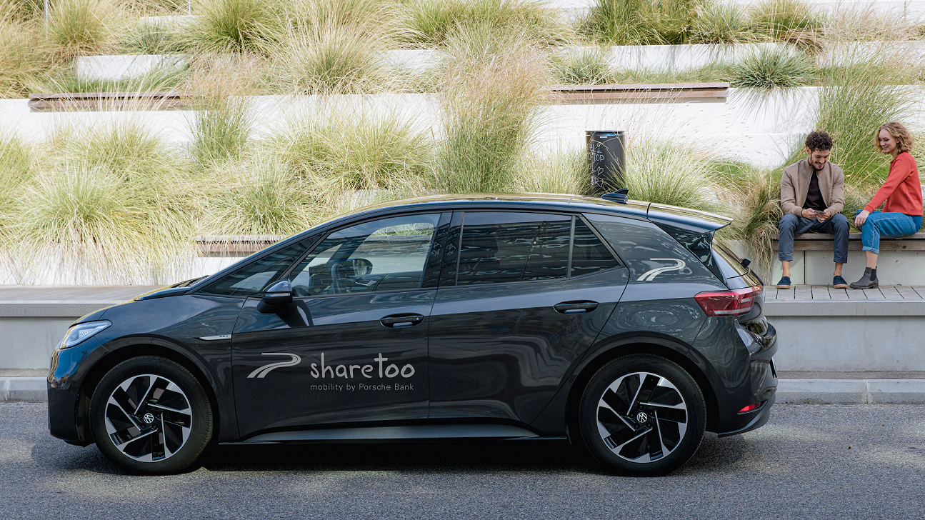 Elektrisches Auto von Sharetoo mit zwei Personen im Hintergrund.